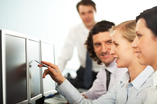 Image of business woman pointing at monitor with colleagues near by