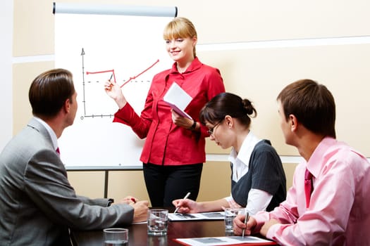 Photo of smart woman pointing at whiteboard at seminar while business partners listening to her