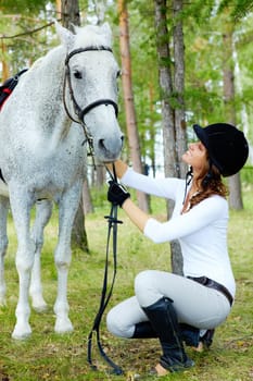 Image of happy female grooming purebred horse outdoors