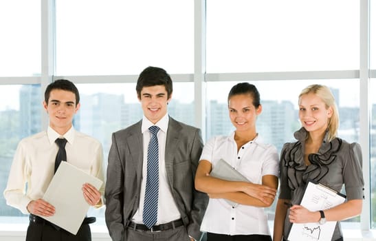 Portrait of smart business group standing in row and looking at camera with smiles