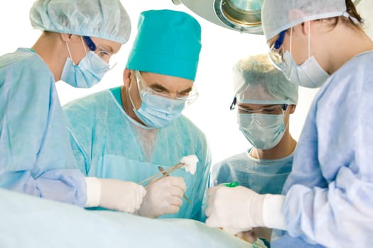 Several surgeons surrounding patient on operation table and looking at her during their work
