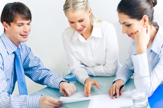 Photo of business partners looking at document and discussing it at meeting