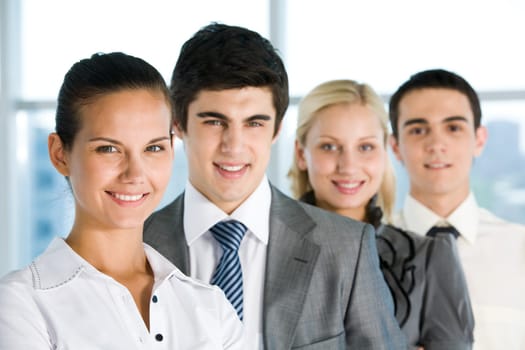 Photo of pretty female looking at camera with her colleagues behind