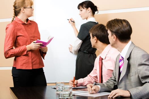 Student and teacher looking at each other at whiteboard with two men staring at them