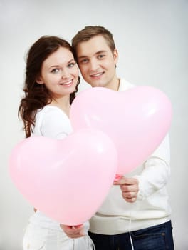 Portrait of two young people holding heart-shaped balloons