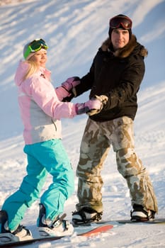 Photo of two snowboarders holding each other by hands while on the snow