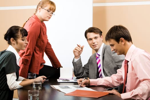 Portrait of successful team listening to young man pointing at document