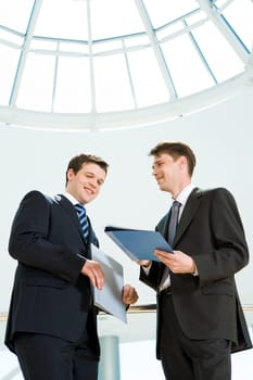 Image of happy businessman looking at document in partners hand