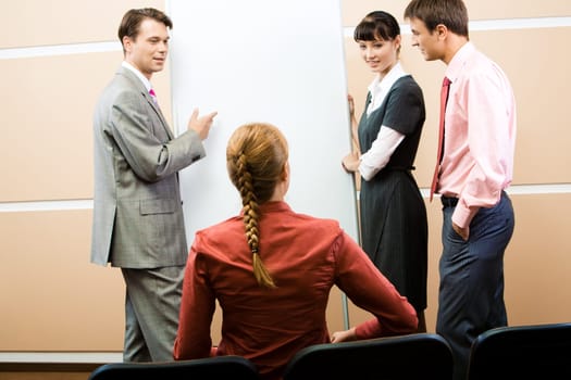 Image of womans back sitting on chair and listening explanation of colleagues on whiteboard