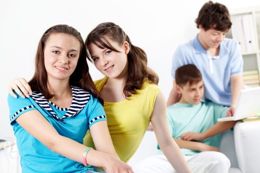 Two teenage girls looking at camera and smiling against their boyfriends