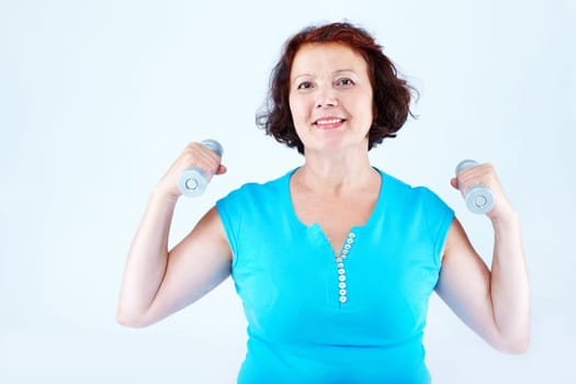 Portrait of healthy middle-aged female practicing exercise with dumbbells