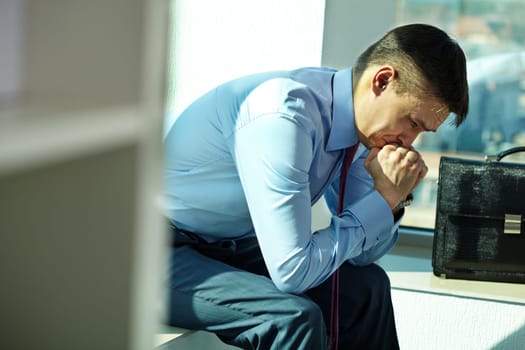 Portrait of troubled man sitting by window and trying to concentrate