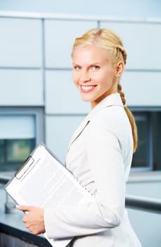 Portrait of elegant businesswoman with clipboard looking at camera