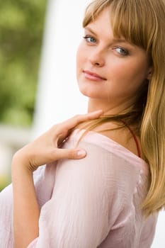 Image of pretty young woman touching her shoulder and looking at camera