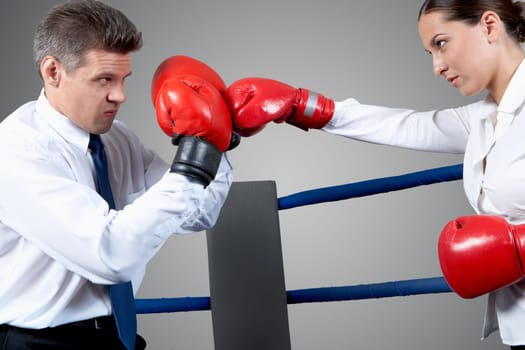 Portrait of aggressive businessman in boxing gloves fighting with serious female opposite him