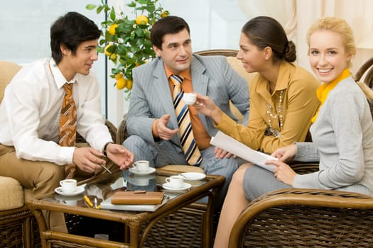Portrait of successful people communicating in office around table and having tea