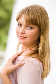 Portrait of fashionable woman touching her shoulder and looking at camera from aside