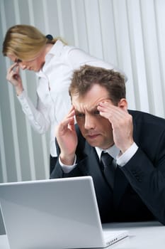 Photo of stressed businessman sitting at workplace and touching his head