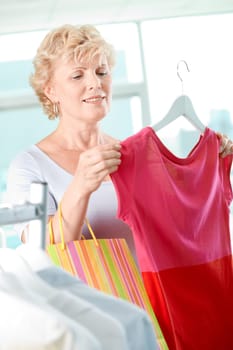 Portrait of middle aged woman choosing new tanktop in clothing department