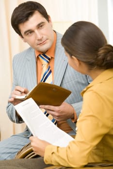 Smart businessman at background listening to his pretty colleague during planning