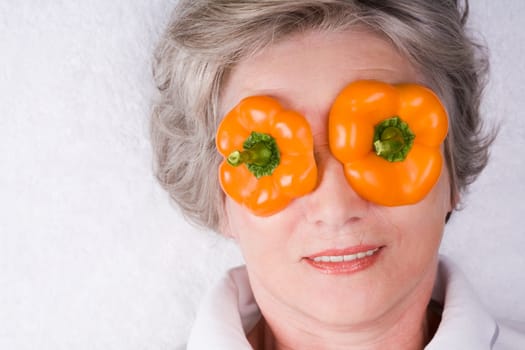 Face of mature woman with pepper slices on her eyes