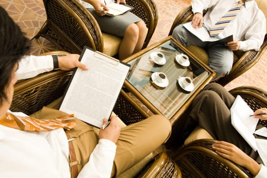 Image of businessman sitting in armchair and holding document at business meeting
