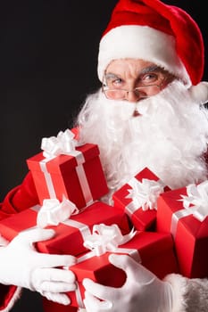 Photo of happy Santa Claus with red giftboxes looking at camera