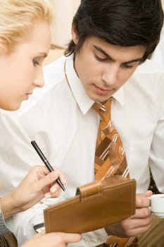 Close-up of young man looking at notepad in females hand