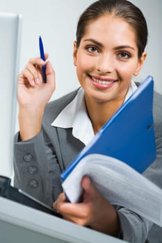 Portrait of smiling business women holding the pen, blue folder and papers in a room