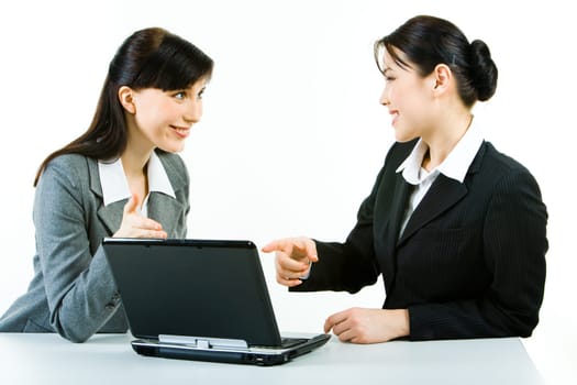 Photo of two attractive women pointing at the laptop monitor with smiles looking at each other