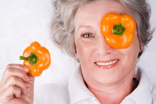 Face of mature woman with taking pepper slice off her eye