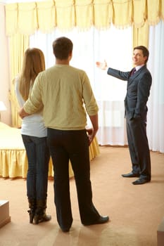Confident businessman showing new flat to young couple