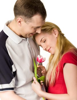 Portrait of pretty woman holding tulip in hand and looking at it with kind man near by
