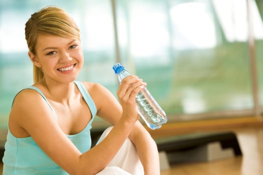 Portrait of lovely girl holding bottle of water in hand and smiling