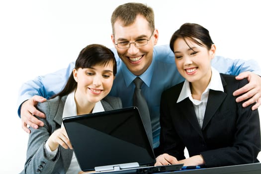 Portrait of smiling young woman sitting at the table with their leader standing behind them and looking at laptop screen together