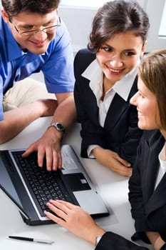 Business team consisting of a man and two women is discussing a strategy in an optimistic manner