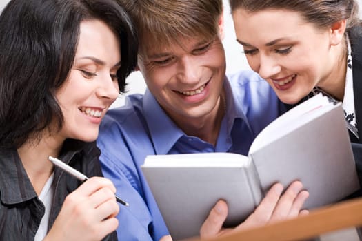Portrait of three business people looking at the notebook