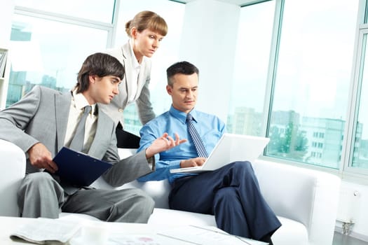 A business team of three sitting in office and planning work