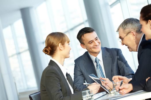 Four businesspeople sitting at table, and interacting