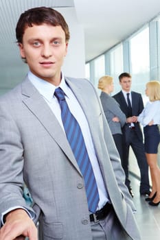 Portrait of a young confident businessman with working team on background