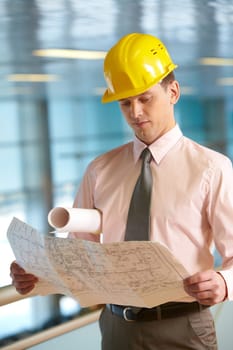 Young architect in helmet examining a housing plan