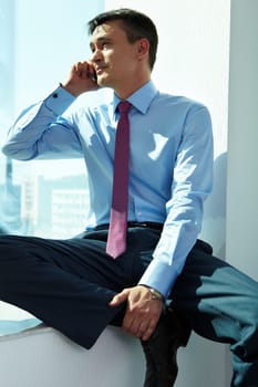 Portrait of handsome man calling by mobile phone in office