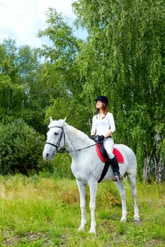 Image of happy female jockey sitting on appaloosa horse outdoors
