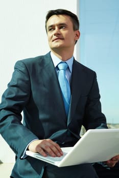 Portrait of confident man with laptop in office