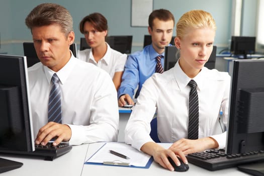 Businesspeople sitting at tables and looking at their monitors
