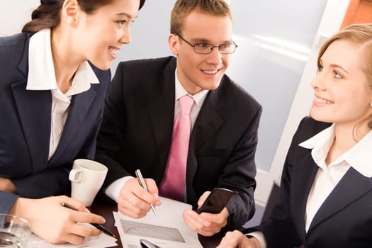 Photo of two confident business people looking at smiling woman in office