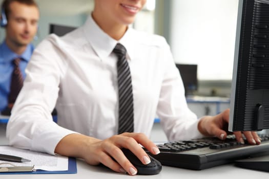 Image of female hand on mouse while typing on keyboard in a working environment