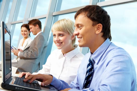 Portrait of executive partners looking at laptop display while working in office