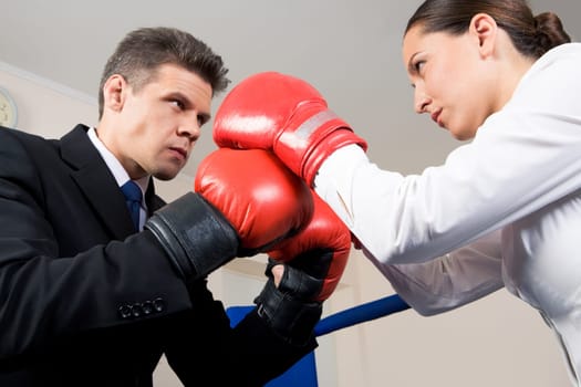 Photo of aggressive business partners in boxing gloves fighting with each other
