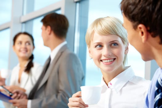 Portrait of young female with cup of coffee looking at her partner while listening to him